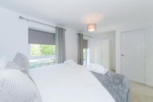 een witte slaapkamer met een bed en een raam bij Arkwright House - Modern Townhouse close to Nottingham City Centre in Nottingham