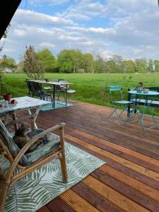 a wooden deck with tables and chairs on a field at Eco-Camping De Helleborus, Yurt, Bell & Safari tent, Pipo, Caravans, Dorms and Units in Groningen