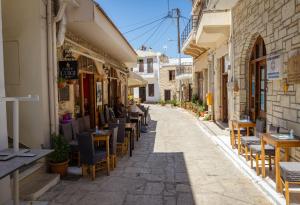 an alley with tables and chairs on a street at FabView Studio Apartments in Panormos Rethymno