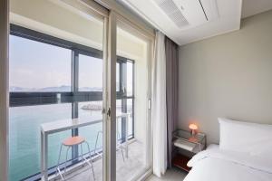 een slaapkamer met een bed en uitzicht op het water bij Shiftdoor Residence Hari in Busan