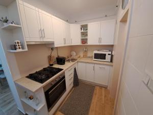 a kitchen with white cabinets and a stove top oven at Lily Apartman Siófok in Siófok