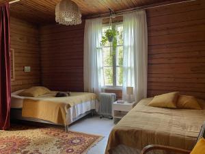 a bedroom with two beds and a window at Villa Ora’s Majatalo in Kolinkylä