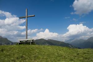 a cross on top of a hill with a bench at Emma's B&B - Self Check-in Hotel in Lungern