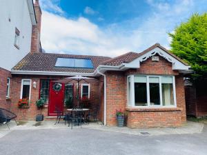 a house with a red door and a table with chairs at Arden Bungalow in Baltray