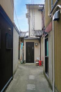 an alley with a black door in a building at 東山の宿 藤屋 in Gionmachi