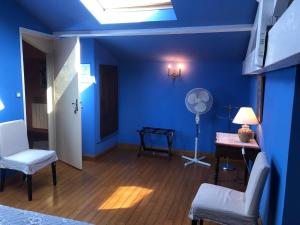 um quarto azul com uma ventoinha, uma mesa e cadeiras em La Petite Provence de Touron em Pujols Gironde