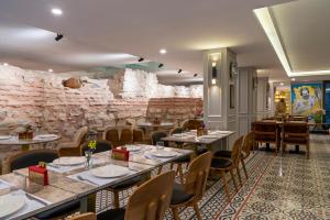 a restaurant with tables and chairs and a stone wall at Royan Hotel Hagia Sophia, a member of Radisson Individuals in Istanbul