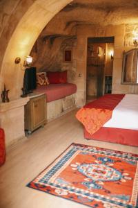 a bedroom with a bed and a tv and a rug at Elaa Cave Hotel in Ortahisar
