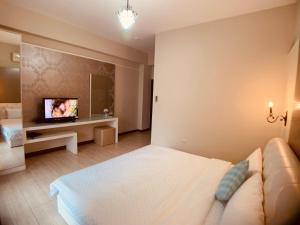 - une chambre avec un lit blanc et une télévision dans l'établissement 居歇座民宿, à Magong