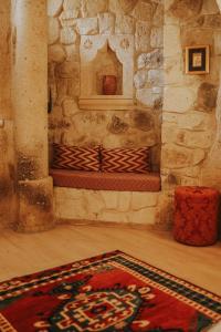 a room with a stone fireplace with a rug on the floor at Elaa Cave Hotel in Ortahisar