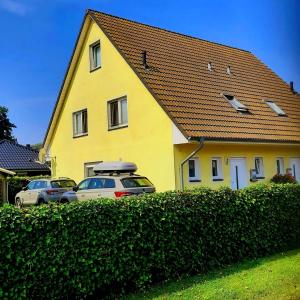 une maison jaune avec deux voitures garées devant elle dans l'établissement MEERerholung, à Zinnowitz