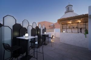 eine Terrasse mit schwarzen Stühlen und Tischen sowie ein Gebäude in der Unterkunft Boutique Hotel Cordial La Niña de Vegueta in Las Palmas de Gran Canaria