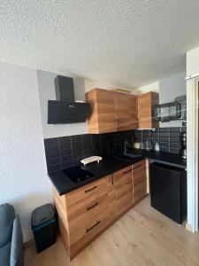 a kitchen with wooden cabinets and a black appliances at LA FOUX D'ALLOS Centre station, vue panoramique Quartier les étoiles 50m des remontées in Allos
