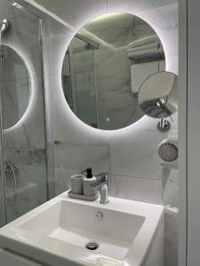 a white bathroom with a sink and a mirror at Thea Luxury Apartment in Tolo