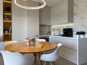 a kitchen with a wooden table and white chairs at Thea Luxury Apartment in Tolo +14 photos