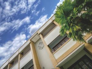 ein Gebäude mit einer Palme davor in der Unterkunft Sima Hotel Kuta Lombok in Kuta Lombok