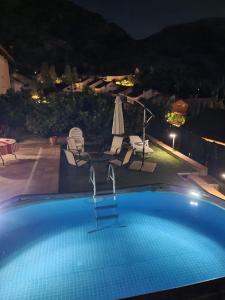 a swimming pool at night with chairs and an umbrella at Villa Alfaguara in Granada