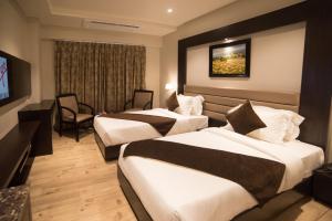 a hotel room with two beds and a television at Hotel Virgo Sumeru in Bhavnagar