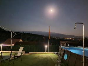 una vista de una piscina por la noche con la luna en Villa Alfaguara, en Granada