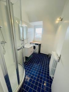 a bathroom with a shower and a blue tile floor at Deauville Serenity - Spacieux & Chic à Place Morny in Deauville