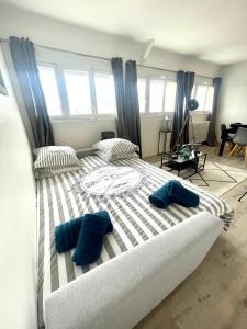 a large bed with two blue pillows on it at Deauville Serenity - Spacieux & Chic à Place Morny in Deauville
