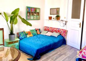 ein Schlafzimmer mit einem blauen Bett und bunten Kissen in der Unterkunft Boutique studio flat at city center in Budapest