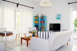 カト・ダラトソにあるHrisi Akti Apt-CHのリビングルーム(白い家具、青い本棚付)