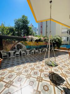 eine Terrasse mit Stühlen und einem Sonnenschirm auf einem Fliesenboden in der Unterkunft Alanya Queen Apart Otel in Alanya