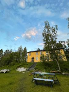 a yellow house with a picnic table in front of it at Villa Ora’s Majatalo in Kolinkylä