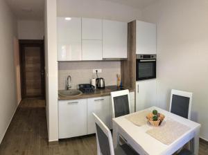 a kitchen with white cabinets and a table with a bowl on it at Apartmani Cupara in Tivat