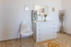 un comò bianco e una sedia in una stanza di Pintadera B&B a Cagliari