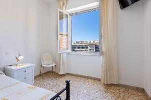 una camera da letto con finestra, letto e sedia di Pintadera B&B a Cagliari