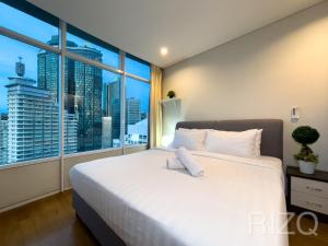 vortex suites klcc by LEAVA في كوالالمبور: غرفة نوم مع سرير أبيض كبير مع نافذة كبيرة