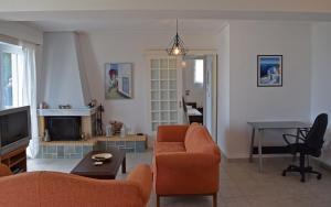 a living room with orange chairs and a fireplace at Corinthian Gulf View in Egira