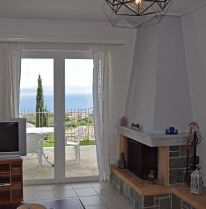 a living room with a fireplace and a television at Corinthian Gulf View in Egira