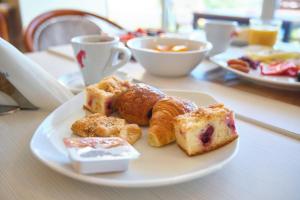 a plate of pastries on a table with cups of coffee at Continental Forum Constanta in Constanţa