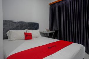 Rempawah的住宿－RedDoorz At Jalan Raya Baturaden，一间酒店客房,床上铺有红色毯子