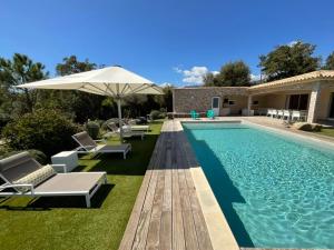 une piscine avec des chaises et un parasol à côté d'une maison dans l'établissement Villa Poggio Rosso - Pool-House & Piscine chauffée, à Sainte-Lucie de Porto-Vecchio