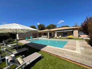une piscine avec des chaises et un parasol à côté d'une maison dans l'établissement Villa Poggio Rosso - Pool-House & Piscine chauffée, à Sainte-Lucie de Porto-Vecchio
