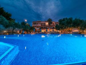 a large swimming pool in front of a building at night at Resort Trcol in Novalja