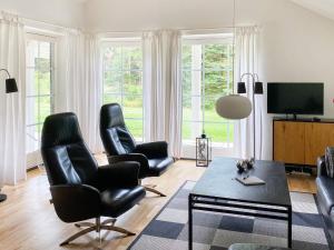 ein Wohnzimmer mit schwarzen Ledersesseln und einem Tisch in der Unterkunft 8 person holiday home in Toftlund in Vestergård