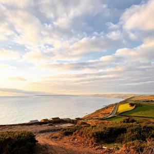 a view of the ocean from a dirt road at Whitsand Bay Tamar Bedroom in Downderry +6 photos