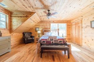Cozy Creekside Log Cabin w Firepit, Hot Tub, WIFI في كليفلاند: غرفة نوم كابينة خشب بها سرير وكرسي