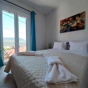 a white bedroom with a large bed and a large window at Jerrys Home Agios Petros in Áyios Pétros