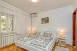 een witte slaapkamer met een bed en 2 ramen bij Matea Rooms in Funtana