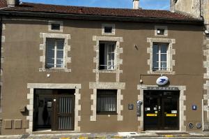 a brown building with a sign on the side of it at Chez Monsieur le directeur de la poste in Piégut-Pluviers