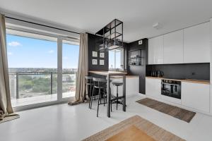 une cuisine avec des appareils en noir et blanc et une grande fenêtre dans l'établissement Gdańsk Comfort Apartments Bastion Wałowa, à Gdańsk