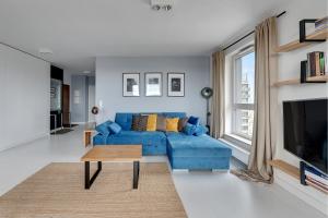 un salon avec un canapé bleu et une télévision dans l'établissement Gdańsk Comfort Apartments Bastion Wałowa, à Gdańsk