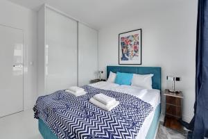 - une chambre avec un lit bleu et blanc et 2 serviettes dans l'établissement Gdańsk Comfort Apartments Bastion Wałowa, à Gdańsk