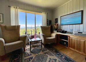 a living room with two chairs and a flat screen tv at Leknes Panorama Lofoten in Leknes